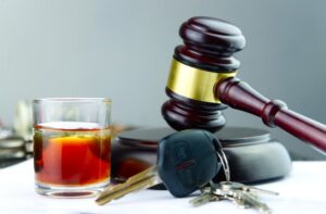 Judge's gavel, whiskey glass, and car key symbolizing the consequences of driving under the influence.