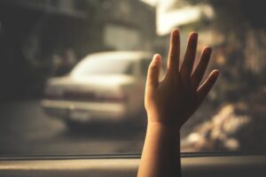 Concept of negligence: A little girl's hand presses against the windshield from inside a car, symbolizing urgency and the dangers of leaving children unattended.